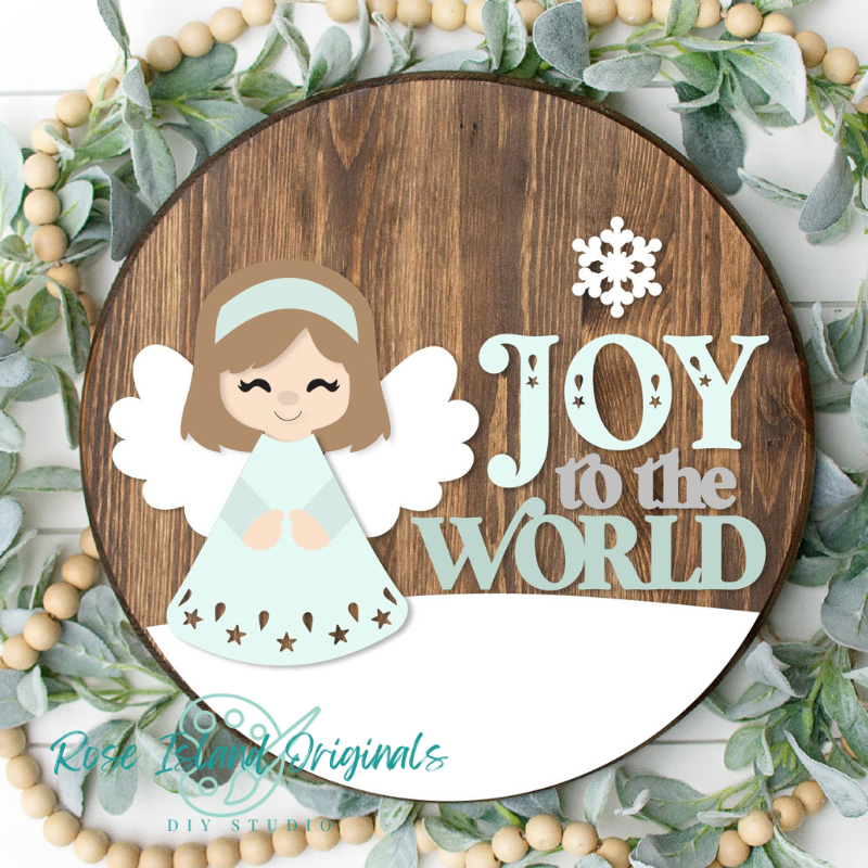 Decorative sign with an angel and 'Joy to the World' text, surrounded by greenery and beads.