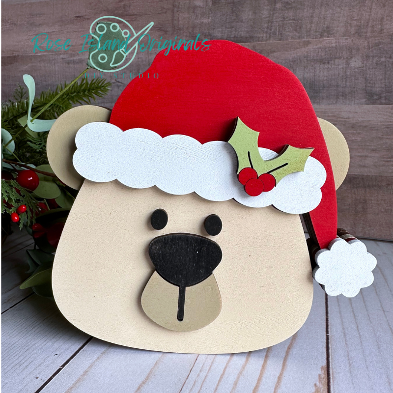 Wooden bear head with Santa hat and holly on a wooden surface