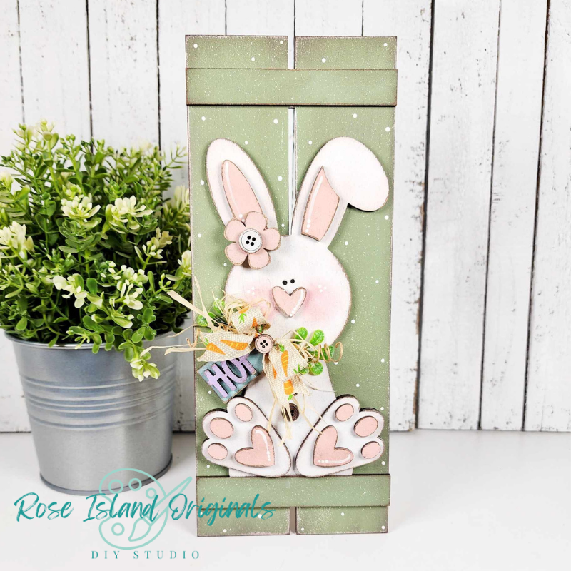 Decorative wooden sign with a bunny design and 'Hug' text, placed against a white wooden panel background.