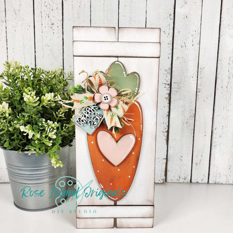 Decorative wooden sign with heart and leaf design on a white wooden background, featuring 'Rose Island Originals' branding.