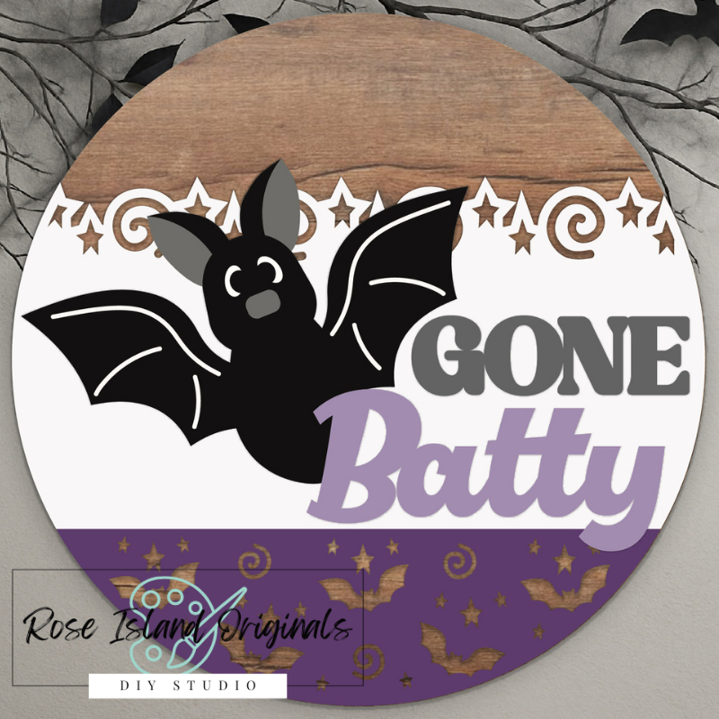 Circular sign with a bat design and 'Gone Batty' text on a wooden background.