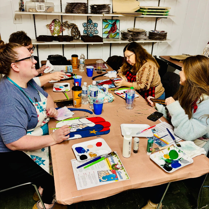 Group of people engaged in a craft activity at a table with art supplies at Rose Island Originals in Sebewaing Michigan.
