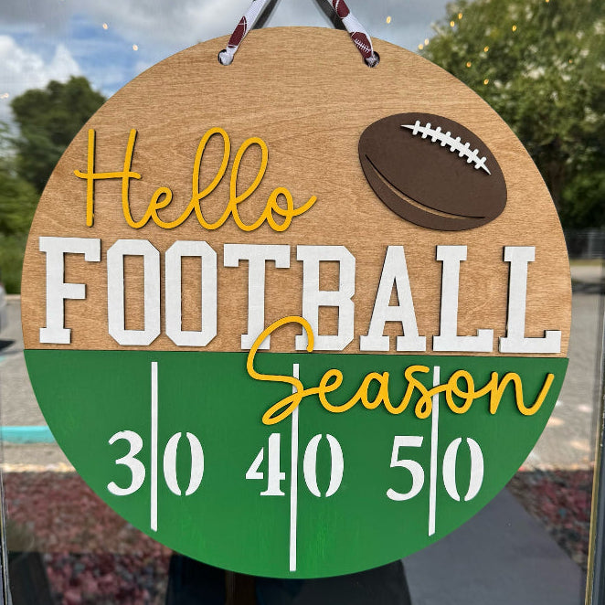 Decorative sign with 'Hello Football Season' text and football graphic, hanging on a door.