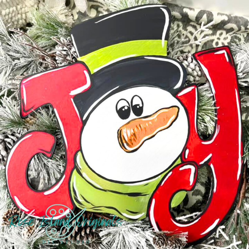 Decorative "JOY" shaped like a snowman with a carrot nose, surrounded by Christmas decorations.