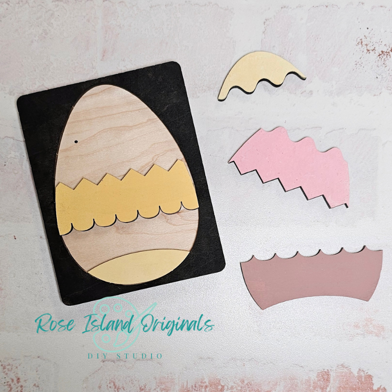 Wooden egg-shaped puzzle with cut-out pieces on a textured surface, branded 'Rose Island Originals'.
