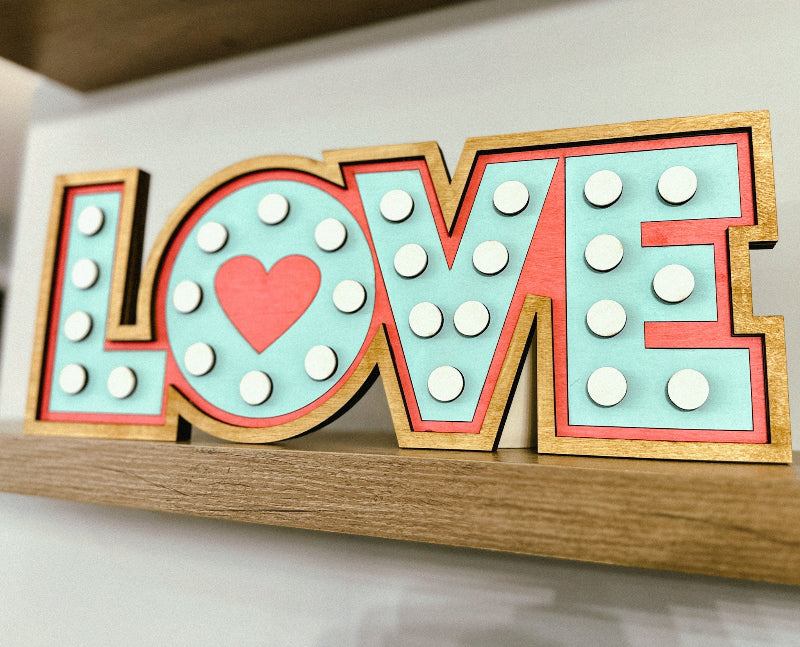 Wood sign with letters spelling LOVE and circles resembling marquee sign