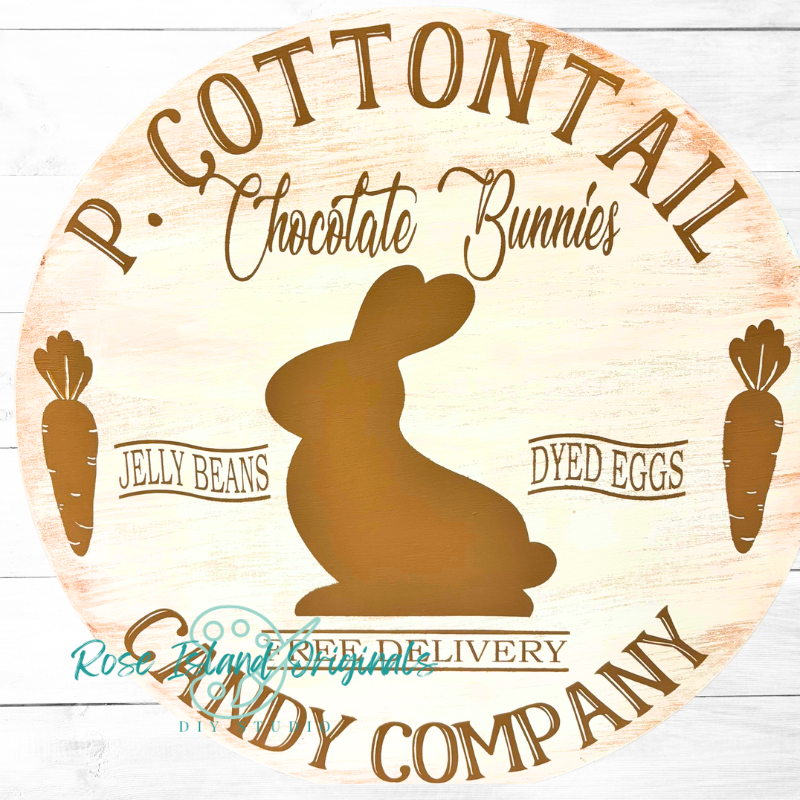 Circular sign with a chocolate bunny silhouette and text about a candy company on a wooden background.
