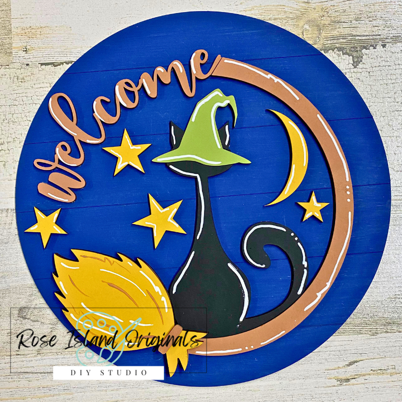 Decorative Welcome sign with a cat, moon, and stars on a blue background.