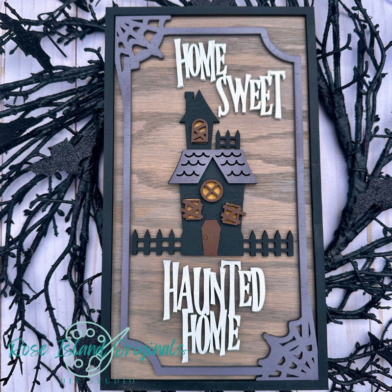 Decorative sign with 'Home Sweet Haunted Home' text and haunted house design on a wooden background.