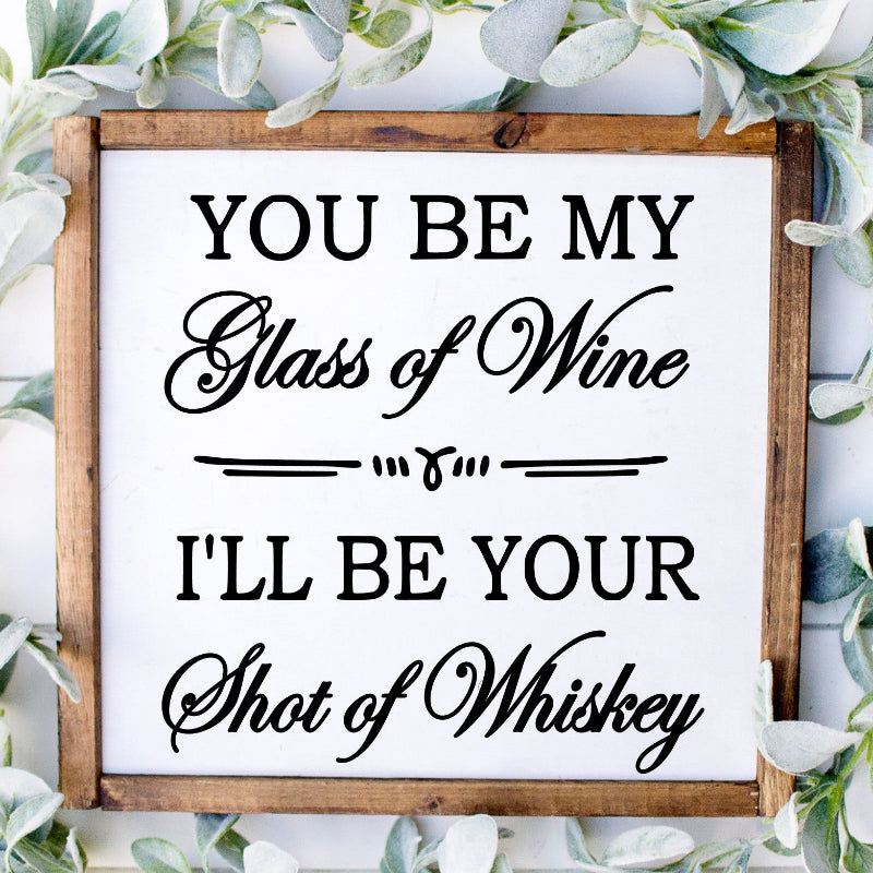 Wooden sign with decorative text surrounded by greenery