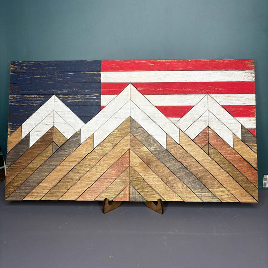 Wood sign featuring American flag in the background with mountains in front in a barn quilt design.