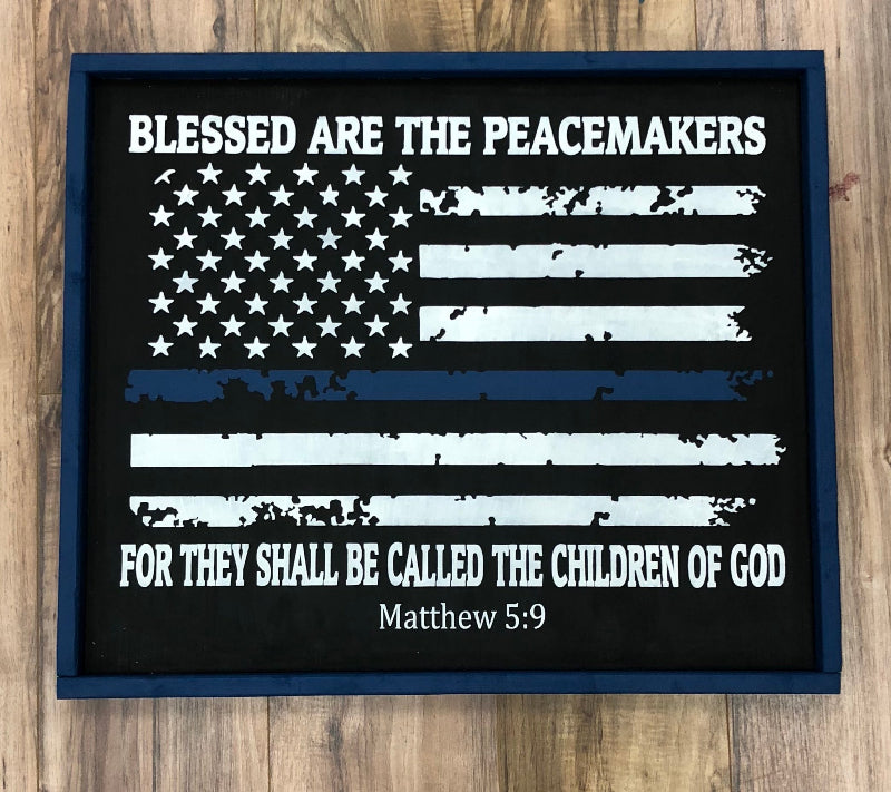 American flag with 'Blessed are the peacemakers' text on a wooden surface