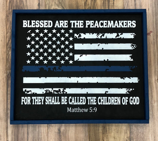 American flag with 'Blessed are the peacemakers' text on a wooden surface
