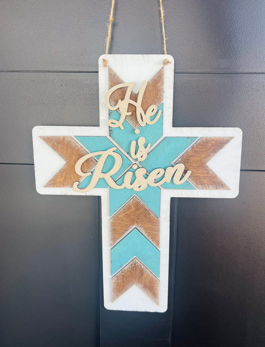 Decorative cross with 'He is Risen' text on a gray background