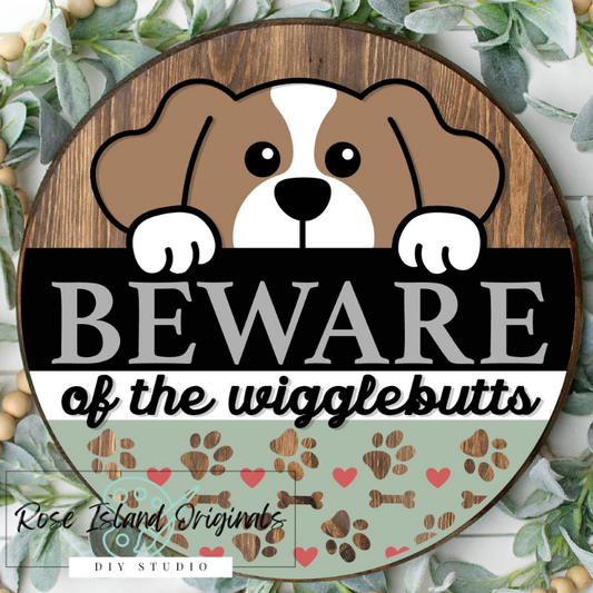 Wooden sign with a dog illustration and text 'Beware of the wigglebutts' surrounded by greenery.