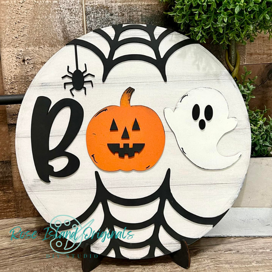 Halloween-themed decorative sign with a pumpkin, ghost, and spider on a wooden background.