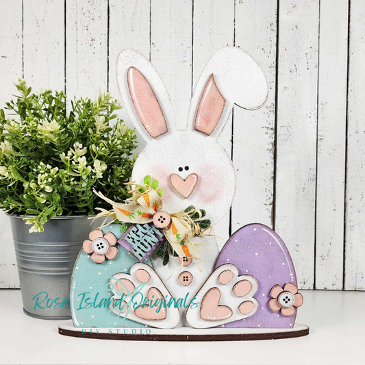 Decorative bunny figure with heart details on a wooden background, featuring 'Rose Island Originals' branding.