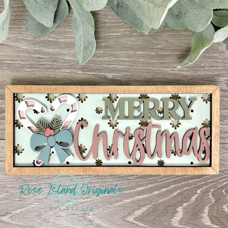 Framed Christmas decoration with 'Merry Christmas' text and candy cane design on a wooden surface.