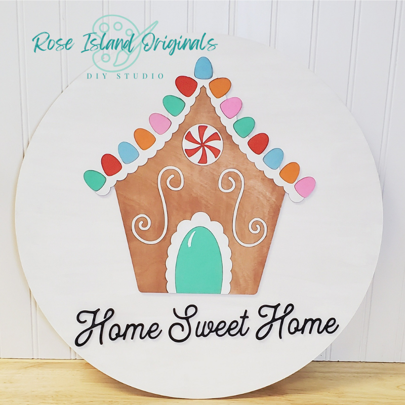 Decorative sign with a gingerbread house design and 'Home Sweet Home' text, branded by Rose Island Originals.