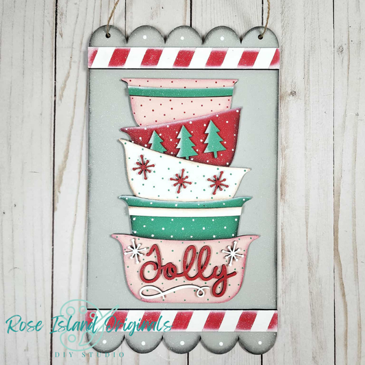 Decorative sign with stacked bowls and 'Jolly' text on a wooden background