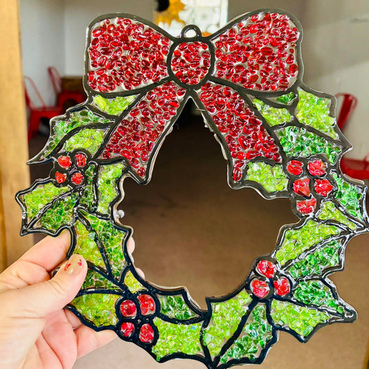 Decorative wreath mirror with red bow held by a hand
