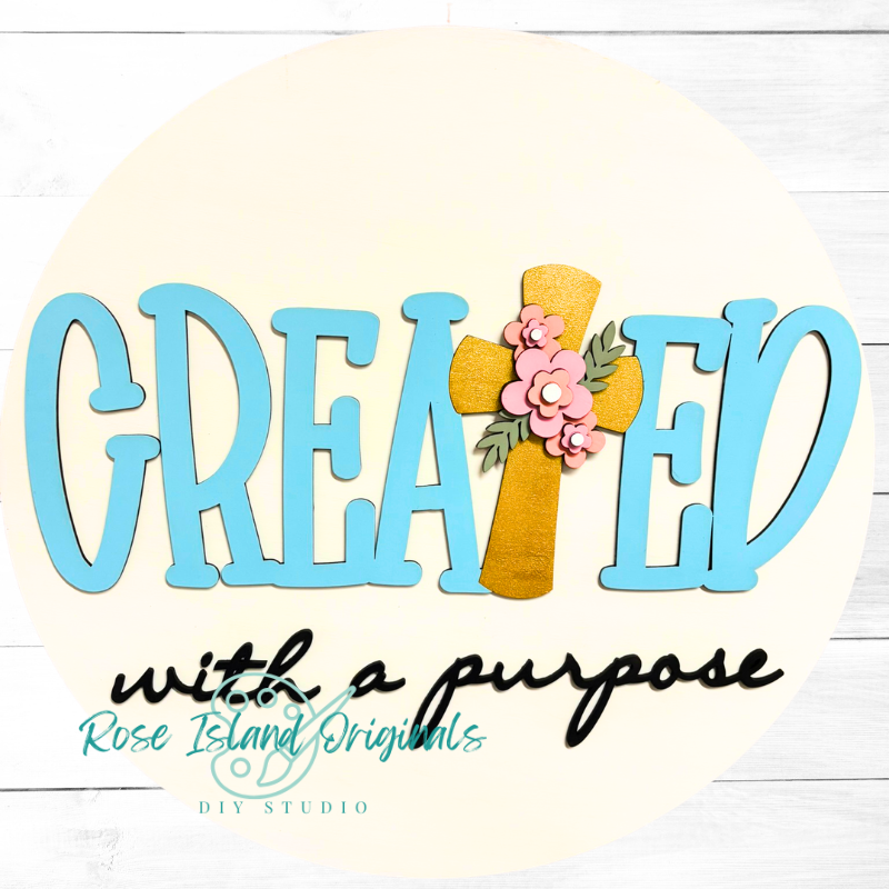 Decorative sign with 'CREATED with a purpose' text and a cross design on a white background.