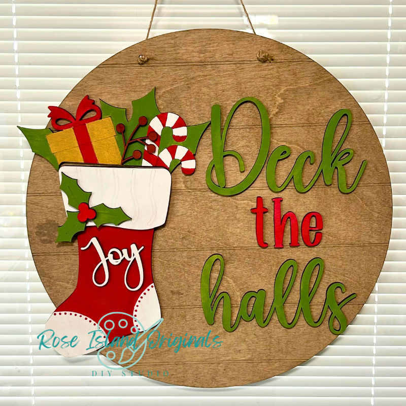 Wooden Christmas sign with a stocking, presents, candy canes, and 'Deck the halls' text.