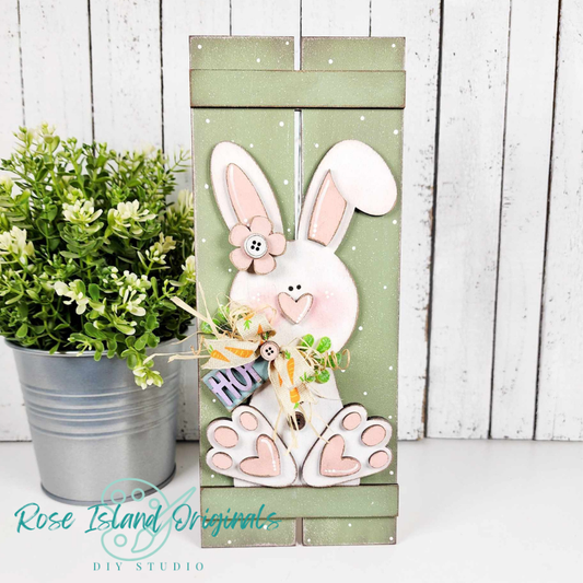 Decorative wooden sign with a bunny design and 'Hug' text, placed against a white wooden panel background.