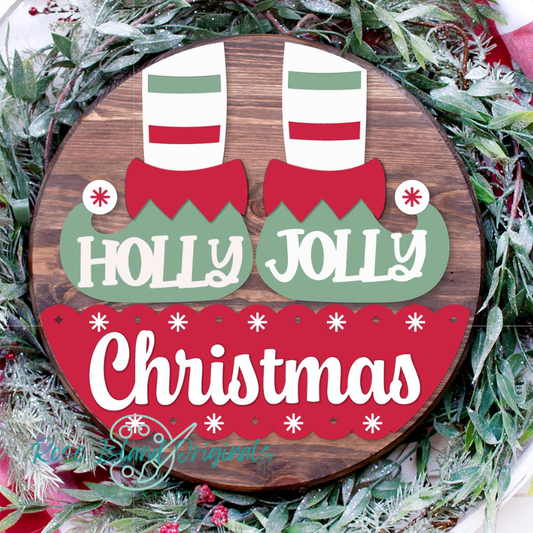 Wooden round sign with elf shoes and 'Holly Jolly Christmas' text on a green leafy background.