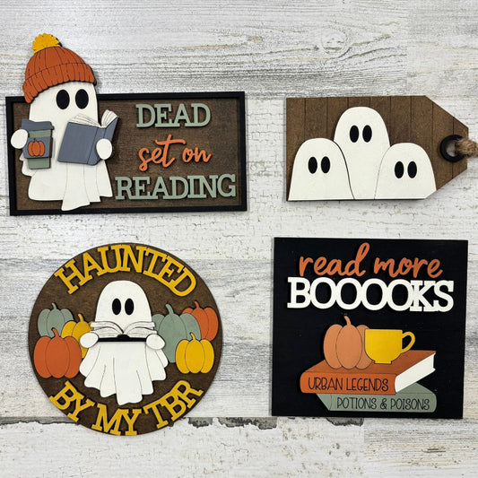Set of Halloween-themed decorative signs with ghosts and autumn elements on a wooden background.