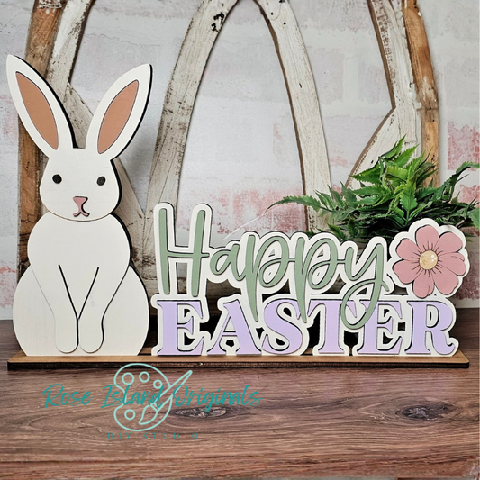 Wooden Easter decoration with bunny, 'Happy Easter' sign, and flower on a wooden surface.
