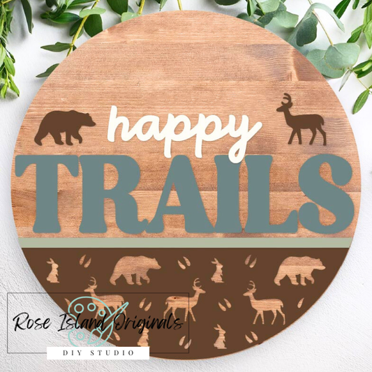 Round wooden sign with 'happy trails' text and animal silhouettes on a white background.