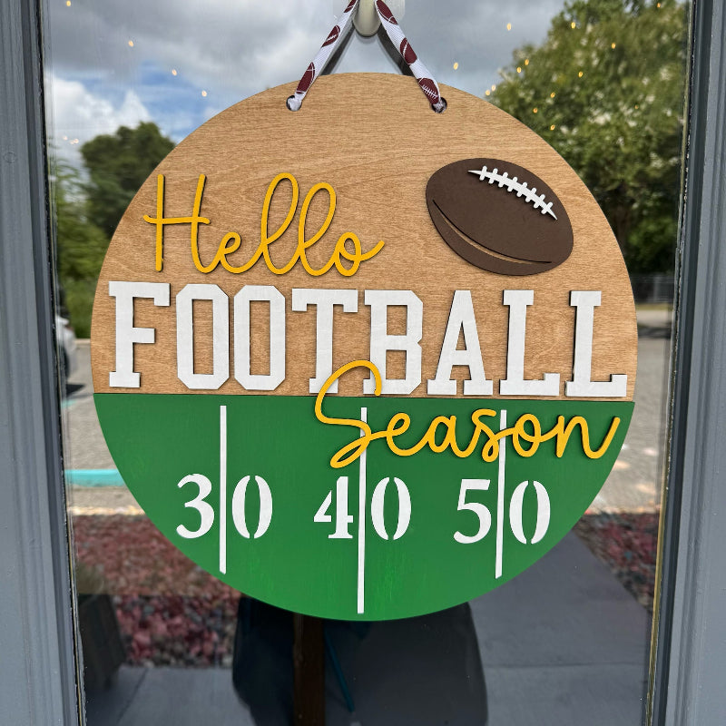 Decorative sign with 'Hello Football Season' text and football graphic, hanging on a door.
