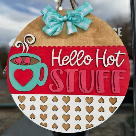 Decorative sign with 'Hello Hot Stuff' text and a coffee cup design, hanging on a glass door.