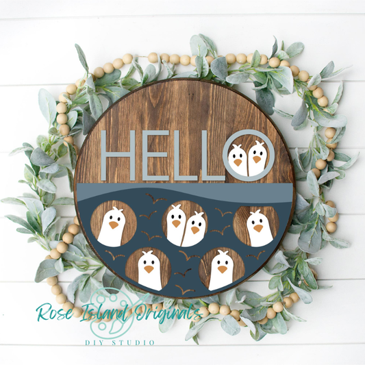 Decorative sign with penguin design and 'HELLO' text, surrounded by greenery and wooden beads.