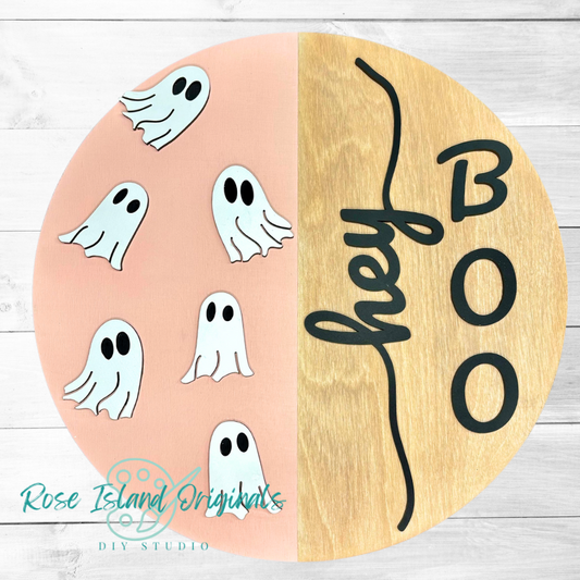 Round wooden sign with laser cut 3D ghosts and 'Hey Boo' text on a pink background