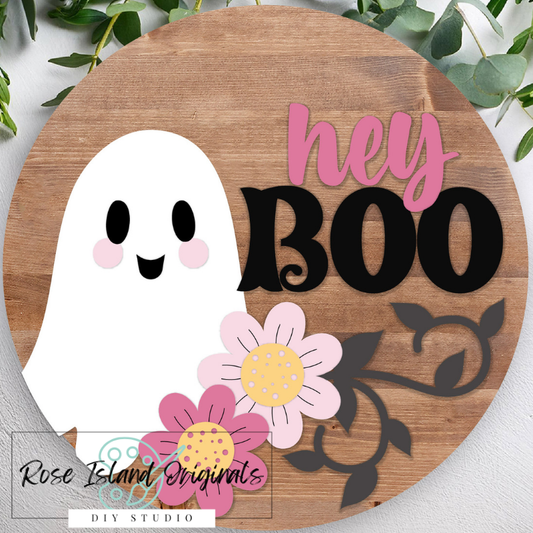 Circular wooden sign with a ghost, flowers, and 'hey BOO' text on a brown wood background.