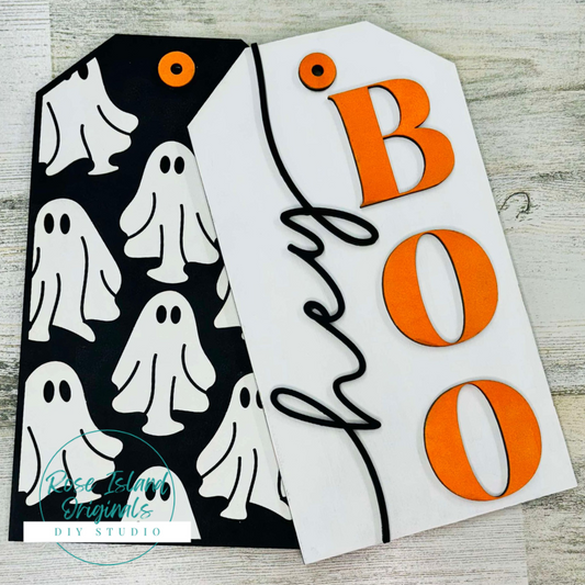 Halloween-themed door tag cutouts with ghosts and 'hey BOO' text on a wooden surface.