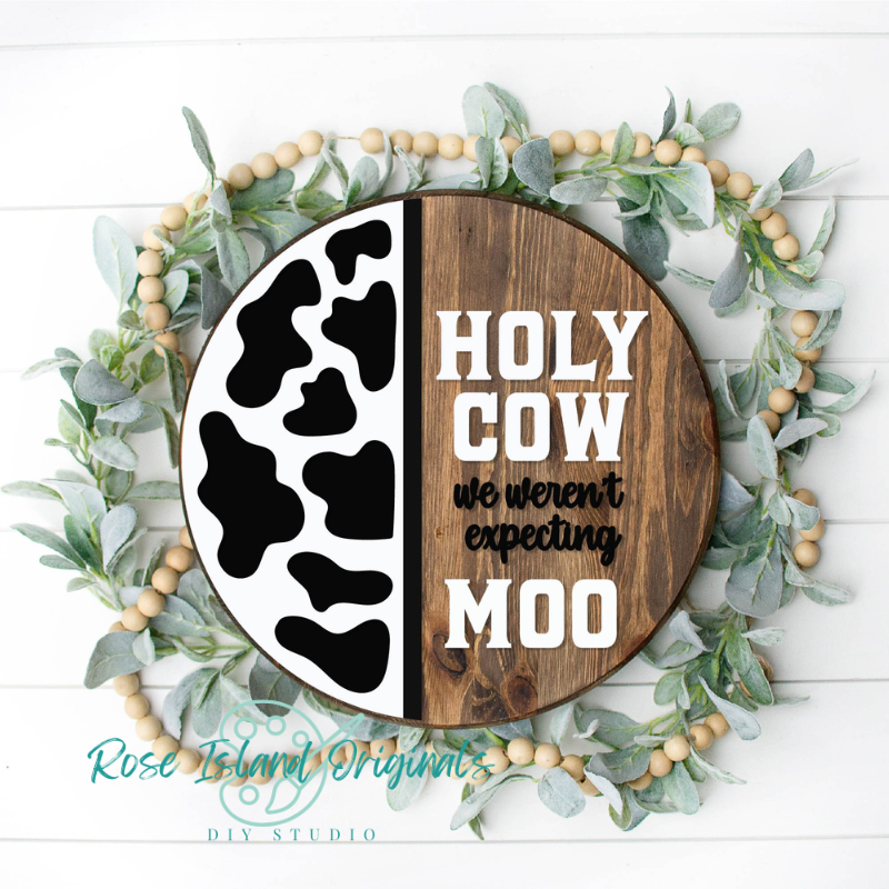 Decorative sign with cow print and text surrounded by greenery and beads on a white background