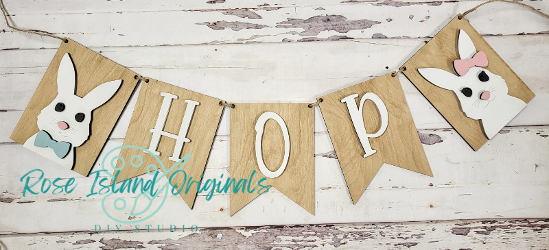 Bunny-themed 'HOPE' banner with decorative elements on a wooden surface, featuring the brand 'Rose Island Originals'.