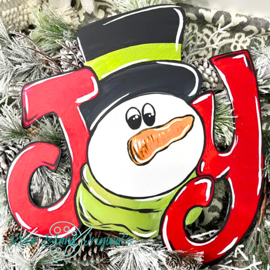 Decorative "JOY" shaped like a snowman with a carrot nose, surrounded by Christmas decorations.