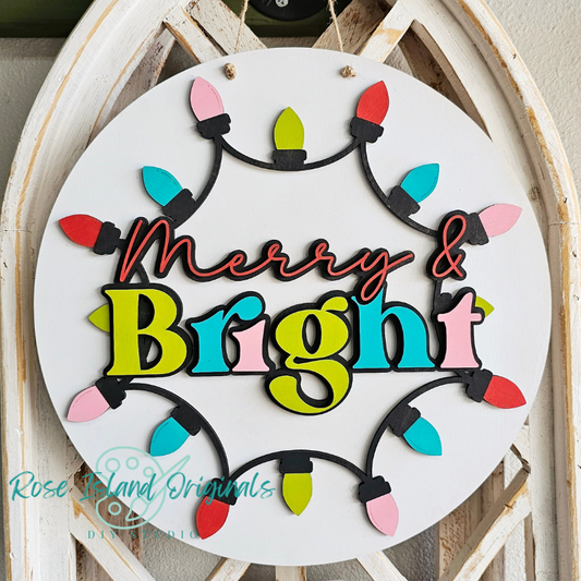 Decorative sign with 'Merry & Bright' text and Christmas lights on a wooden background.