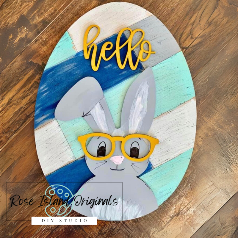 Decorative sign with a rabbit face wearing glasses and the word 'hello' on a wooden surface.
