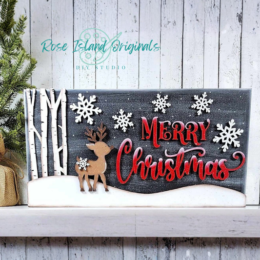 Decorative Christmas sign with reindeer, snowflakes, and 'Merry Christmas' text on a wooden shelf.