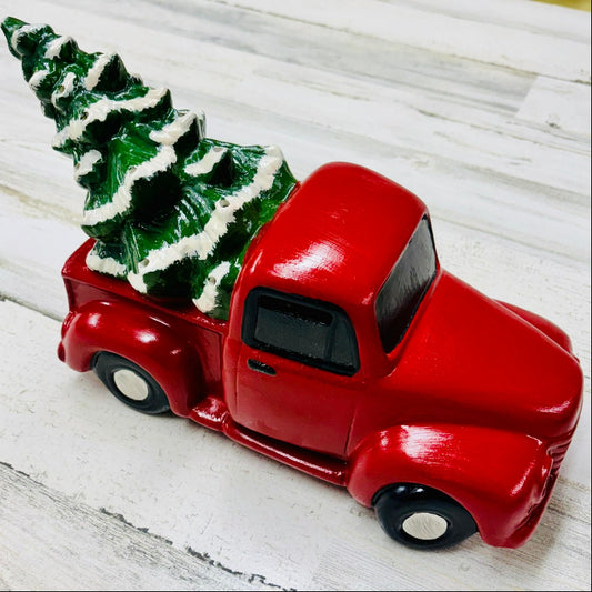 Red toy truck with a Christmas tree on a white wooden surface