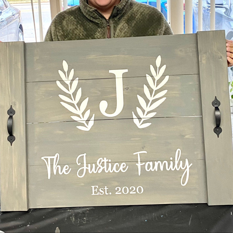Person holding a wooden sign with 'The Justice Family Est. 2020' text