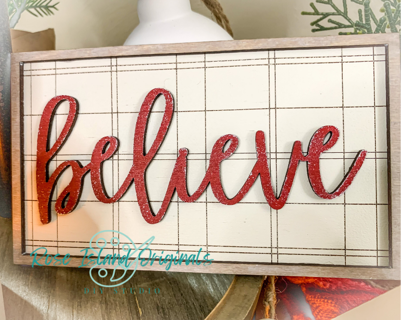 Decorative sign with 'believe' in red letters on a grid background