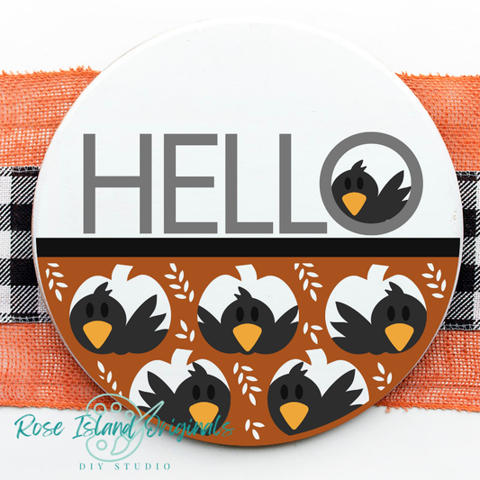 Round sign with word hello has crows looking out pumpkin cutouts on a white background