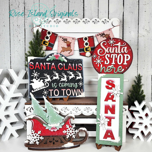 Set of Christmas-themed decorative signs with Santa Claus and winter elements on a wooden background.