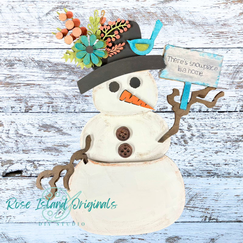 Decorative snowman with a hat, flowers, and a sign on a wooden background
